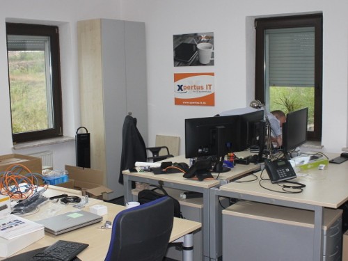 XPERTUS JETZT IN MOGENDORF 8 Büro von Xpertus IT mit mehreren Arbeitsplätzen, Computern, Büromöbeln und Kabeln. Fenster bieten Ausblick auf die umliegende Landschaft.
