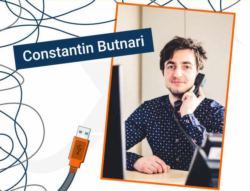 Portrait von Constantin Butnari, der am Telefon sitzt und in einem Büro arbeitet. Im Hintergrund ist ein Computer und ein USB-Kabel sichtbar.